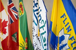 The Canadian, Manitoban, Saskatchewan, and two Flin Flon flags hang from short flag poles lined up.