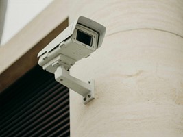 A security camera on a beige wall.